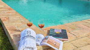 A poolside setting with a towel, two glasses of red wine, and a book titled 'Valles Vinos de España' on a stone ledge. - Casa Rural Viña Romanito Jerez de la Frontera by Ruralidays (Cádiz)