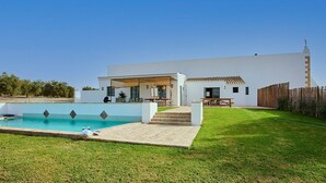 A modern house with a swimming pool, a patio, and a wooden fence.