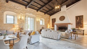 A spacious living room with stone walls, a fireplace, and a high ceiling.