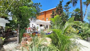 Ein Innenhof mit Blumentöpfen, ein weißes Gebäude mit rotem Dach und einem strahlend blauen Himmel.