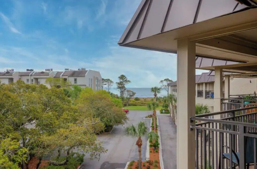 A residential building with a covered outdoor area, a view of the sea, and a well-maintained garden.