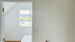 Et soveværelse med seng, vindue og lampe.