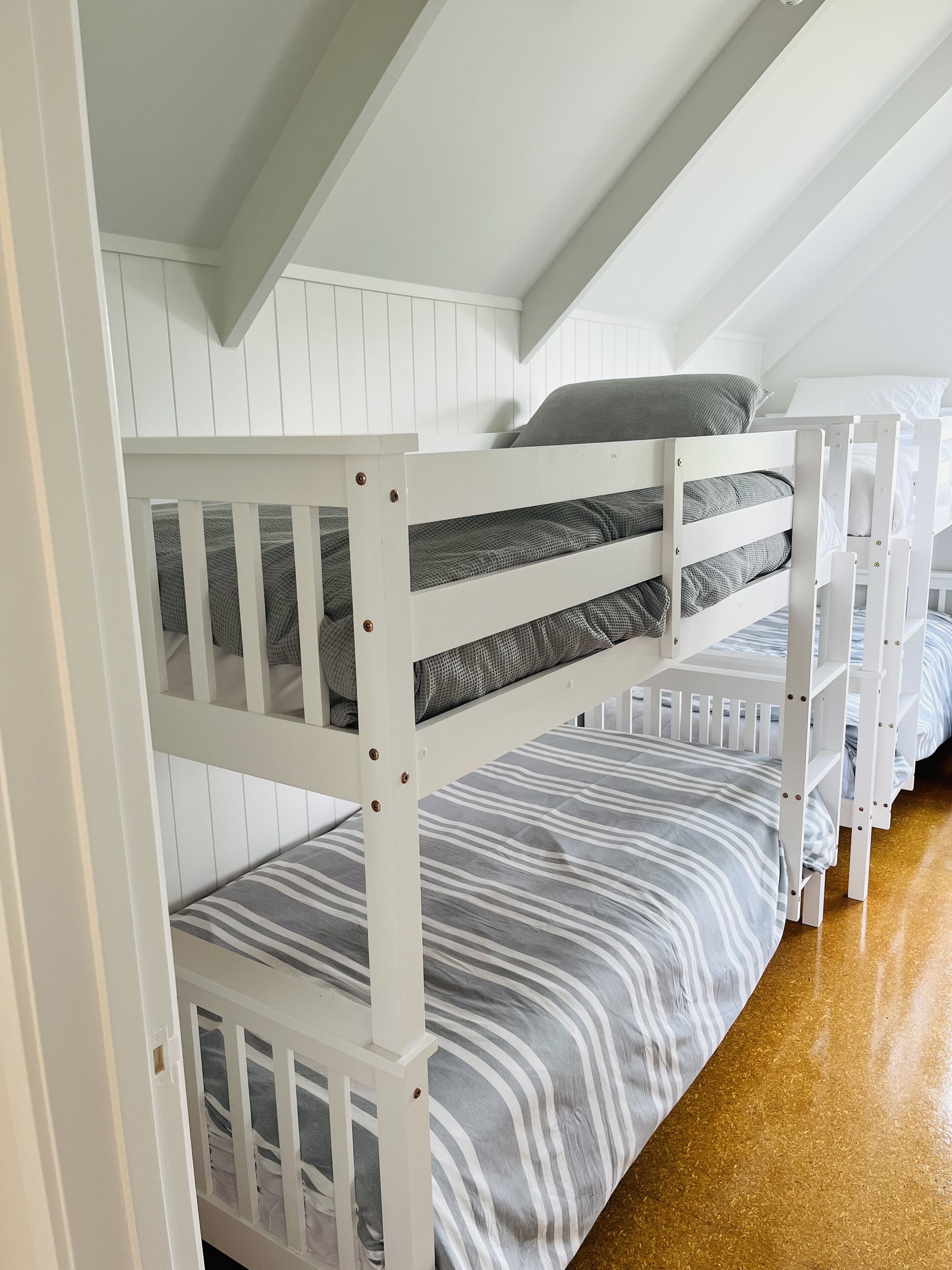 A bunk bed room with white walls and a sloped ceiling.