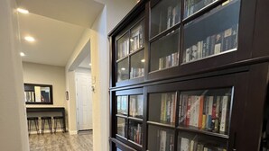 A hallway with a dark wooden bookshelf filled with books, a wooden floor, and a white door at the end. - Coastal Vibes • Cal King Bed • Trails (Folsom)