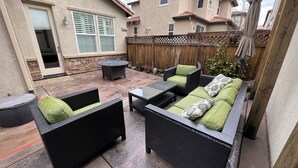 A patio area with wicker furniture, a round table, and a wooden fence. - Coastal Vibes • Cal King Bed • Trails (Folsom)