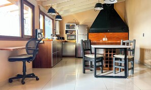 A compact kitchen with a dining area, a coffee machine, a refrigerator, and a window.