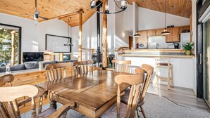 A spacious dining area with a wooden table and chairs, a chandelier, and a kitchen in the background. - Secluded 3bed/Hot tub/Views (Fairplay)