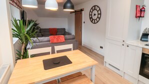 Een moderne keuken met witte kastjes, een houten eettafel en hanglampen.