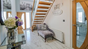 Ein modernes Interieur mit Marmorboden, einer Treppe mit Holzsstufen, einer Chandelier und einem Schild mit der Aufschrift 'Willkommen in unserem Zuhause'.
