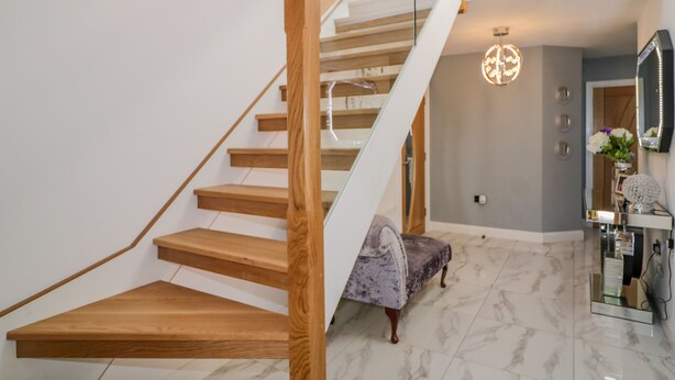 Eine Holztreppe mit Glasgeländern, die zu einer zweiten Etage führt.