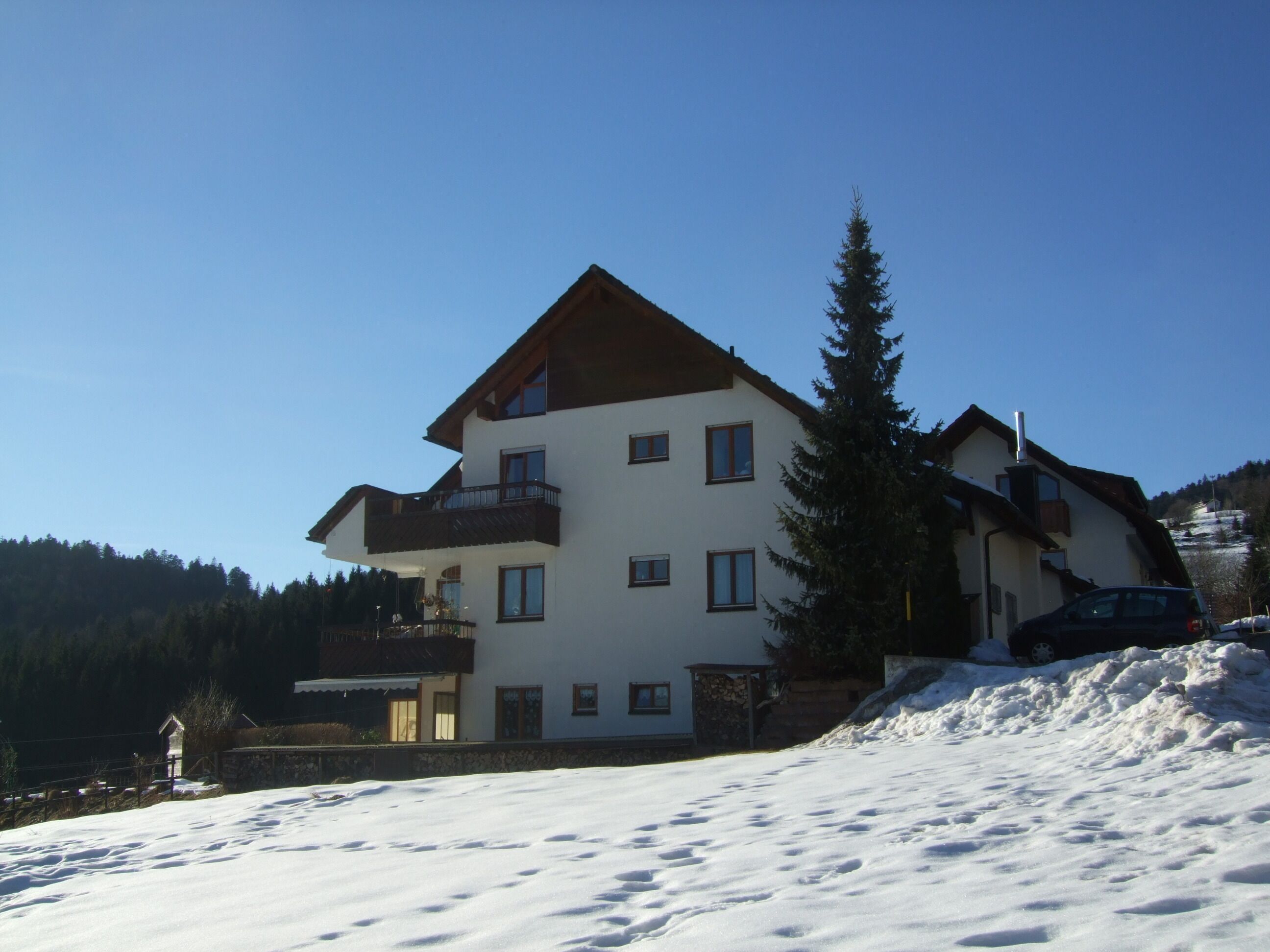 A multi-story building with a sloped roof, balconies, and a snow-covered ground.
