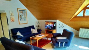 Ein gemütliches Wohnzimmer mit einem blauen Sofa, einem Couchtisch und einem Fernseher.