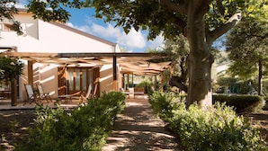 A covered outdoor area with wooden furniture and a pathway leading to a building.