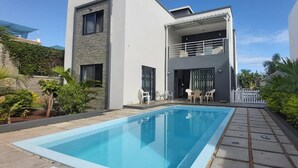 A modern two-story house with a swimming pool, outdoor seating, and lush greenery. - Beautiful House With Private Pool in Mauritius (Albion)