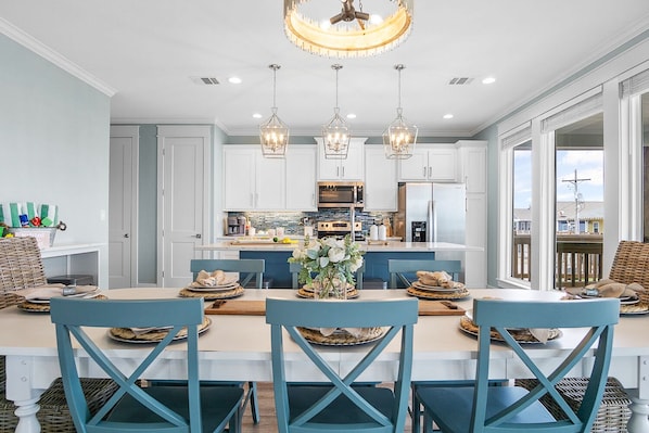 Une cuisine moderne avec des meubles blancs, un îlot central et des luminaires suspendus.
