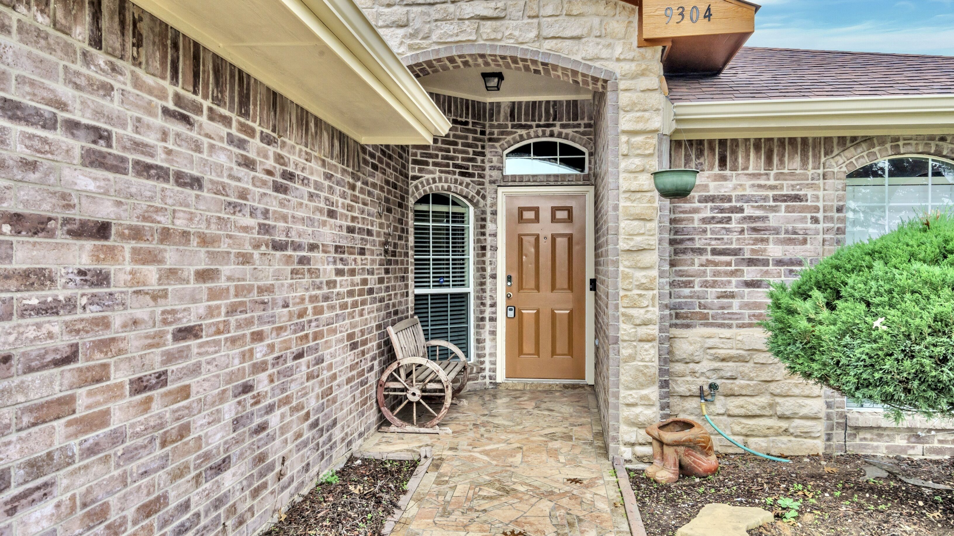 A brick house with a stone archway, a wooden door, and a mailbox.