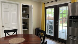 A kitchen with a refrigerator, a dining table with chairs, a window with a view of the backyard, and a door leading to a pantry. - Modern Home w/ Free WiFi near Seaworld! Small Dog Friendly (San Antonio)