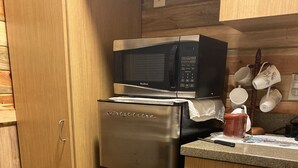 A kitchen with a stainless steel Frigidaire refrigerator, a West Bend microwave, wooden cabinets, a granite countertop, and a tiled backsplash. - Cabin/Farmhouse w/fire pit and wide open spaces (Haslet)