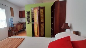 Ein Hotelzimmer mit Bett, Schreibtisch, Stuhl, Wasserspender, Kleiderschrank und einer Wanddekoration.