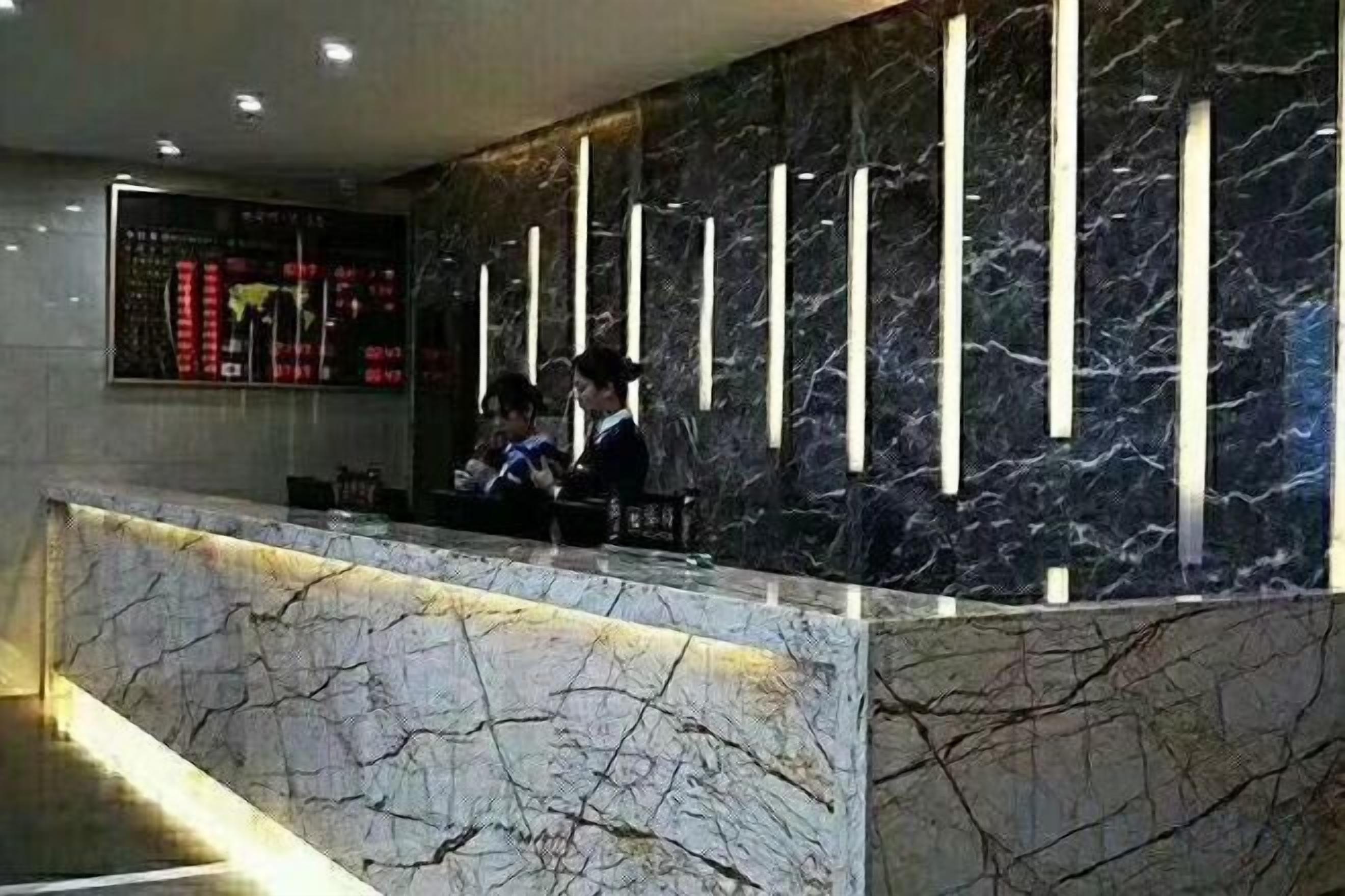 A reception desk with a marble counter and vertical light fixtures.
