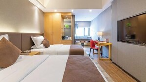 A hotel room with two beds, a desk, a chair, a TV, and a kitchenette. - Yong'anzhou Hotel (Mengshan)