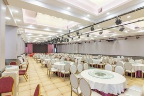 A banquet hall with round tables, chairs, and a stage area. - Yong'anzhou Hotel (Mengshan)