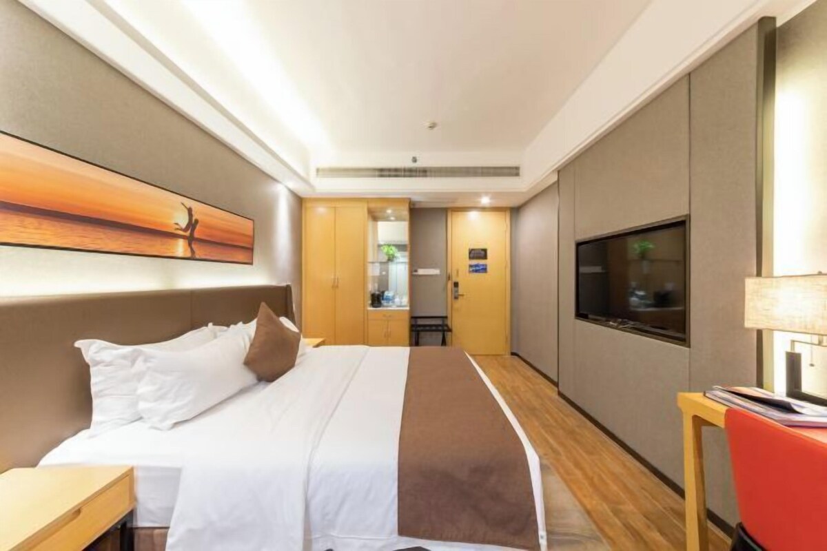 Een hotelkamer met een bed, een televisie, een bureau en een schilderij aan de muur.