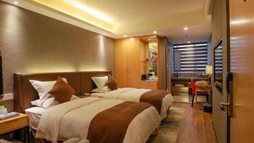 A hotel room with two beds, a desk, a chair, a mirror, and a window with blinds.