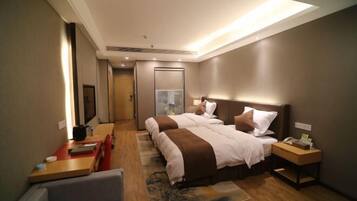 A hotel room with two beds, a desk, a chair, and a small table.