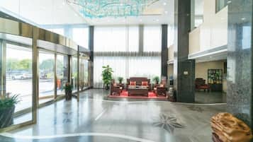 A spacious lobby with a seating area, large windows, and a modern chandelier.