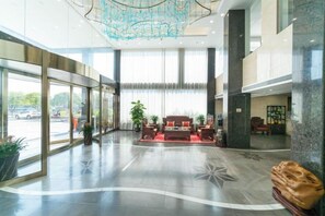 Un vestíbulo amplio con zona de estar, ventanas grandes y una lámpara moderna.