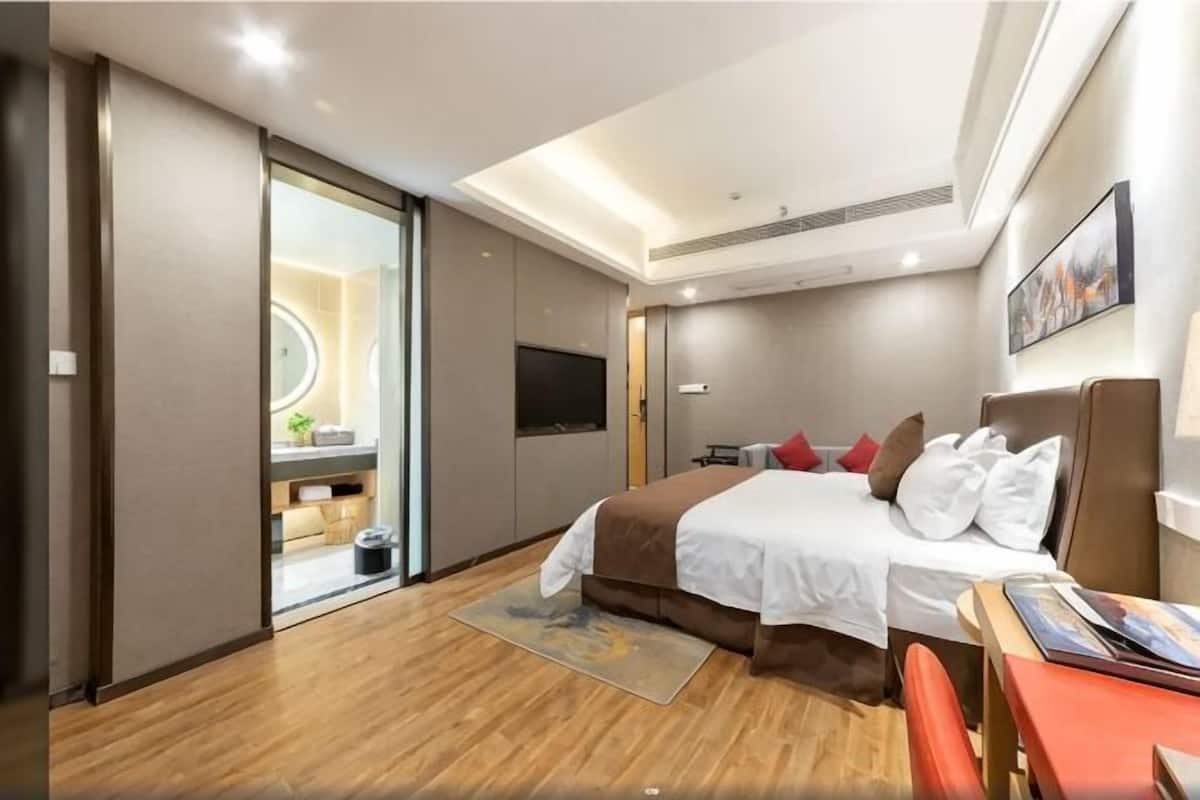 Hotellihuone, jossa on sänky, työpöytä, televisio ja liukuovi, joka johtaa kylpyhuoneeseen.