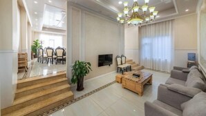 A spacious living room with a staircase, a chandelier, and a television. - Yong'anzhou Hotel (Mengshan)