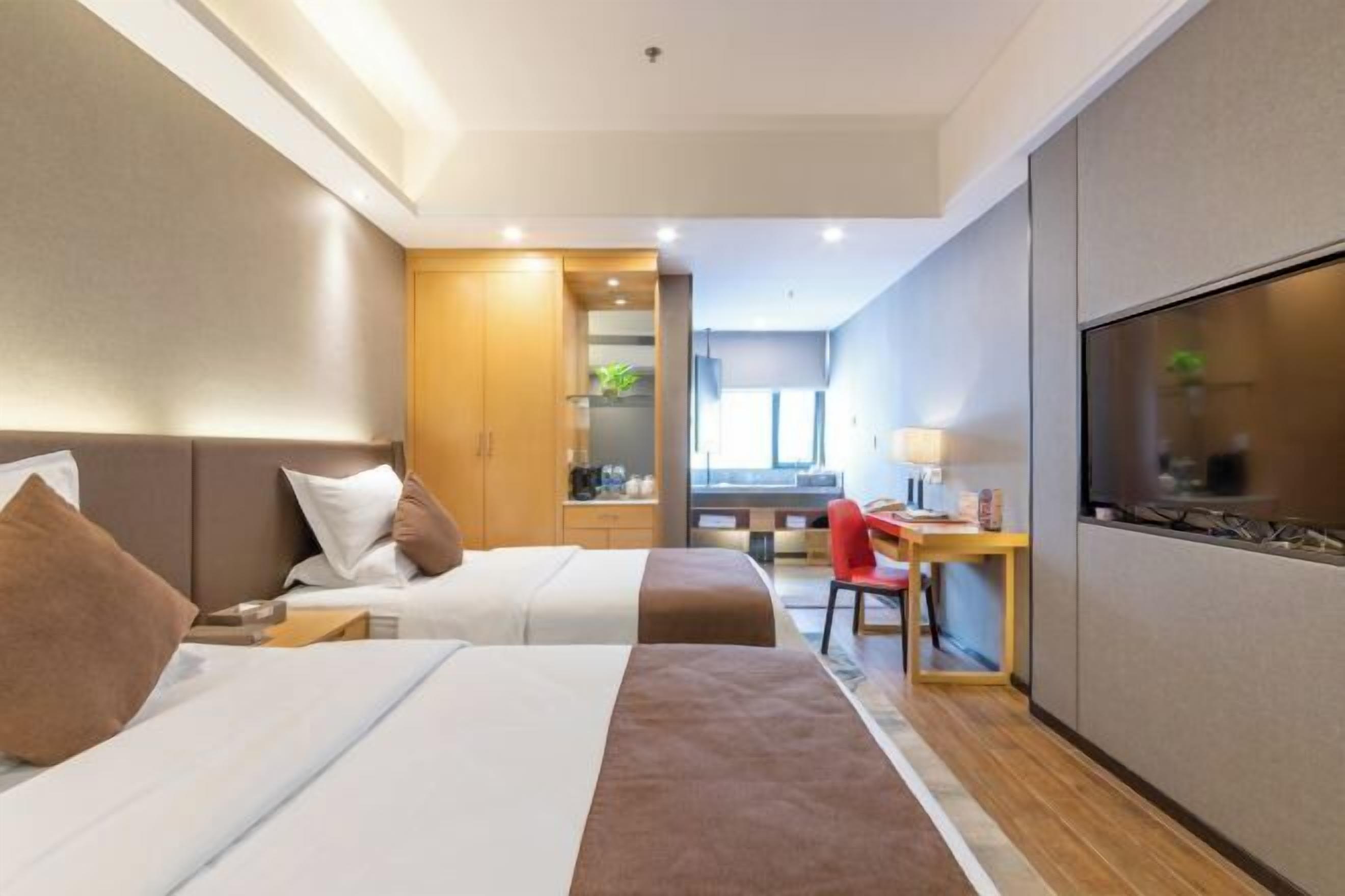 Ein Hotelzimmer mit zwei Betten, einem Schreibtisch, einem Stuhl und einem Fernseher.