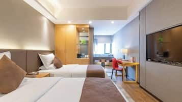 Ein Hotelzimmer mit zwei Betten, einem Schreibtisch, einem Stuhl und einem Fernseher.