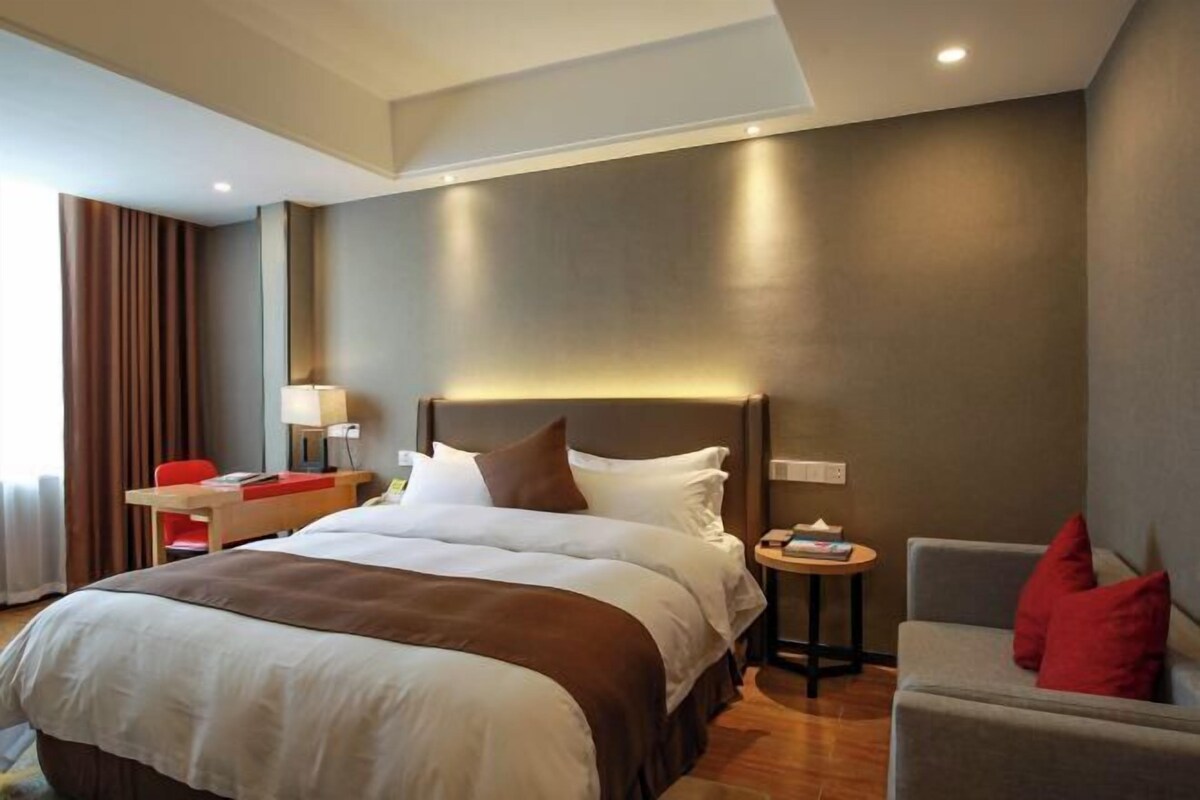 Een moderne hotelkamer met een groot bed, een bureau, een stoel en een kleine tafel.