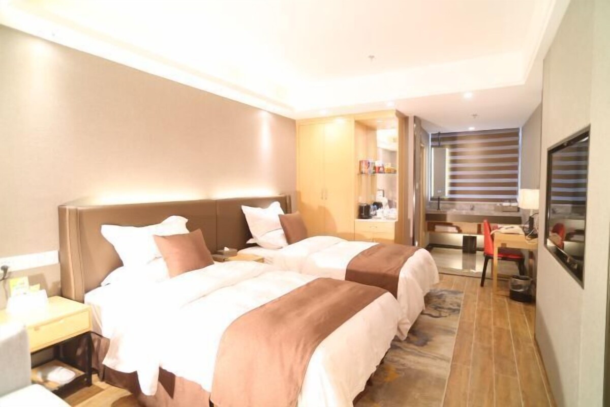 Een hotelkamer met twee bedden, een bureau en een spiegel.