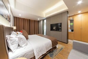 Een moderne hotelkamer met een groot bed, een flatscreen-tv, een kledingkast en een zithoek.