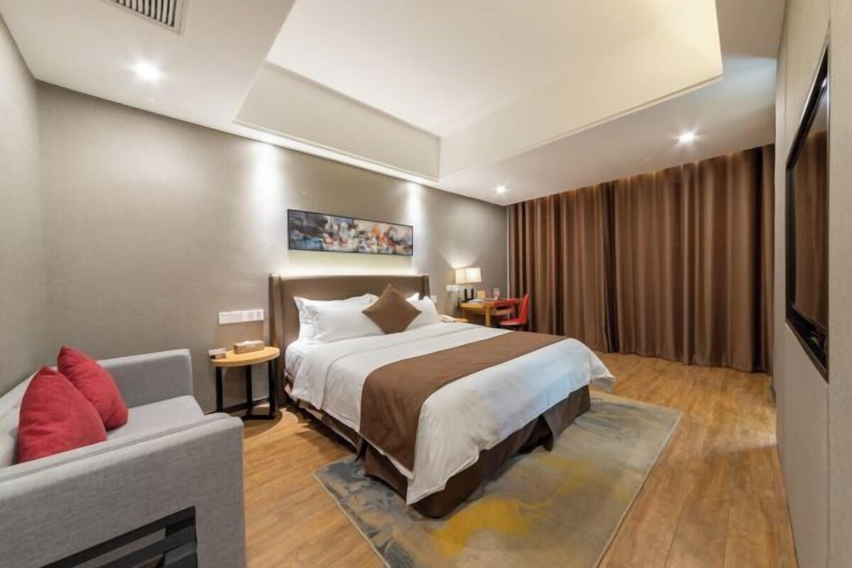 Een moderne hotelkamer met een groot bed, een bank, een klein tafeltje en een televisie.