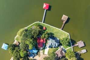 Eine Luftaufnahme eines Seeanwesens mit Steg, einem Gebäude mit rotem Dach und einer Struktur mit blauem Dach.