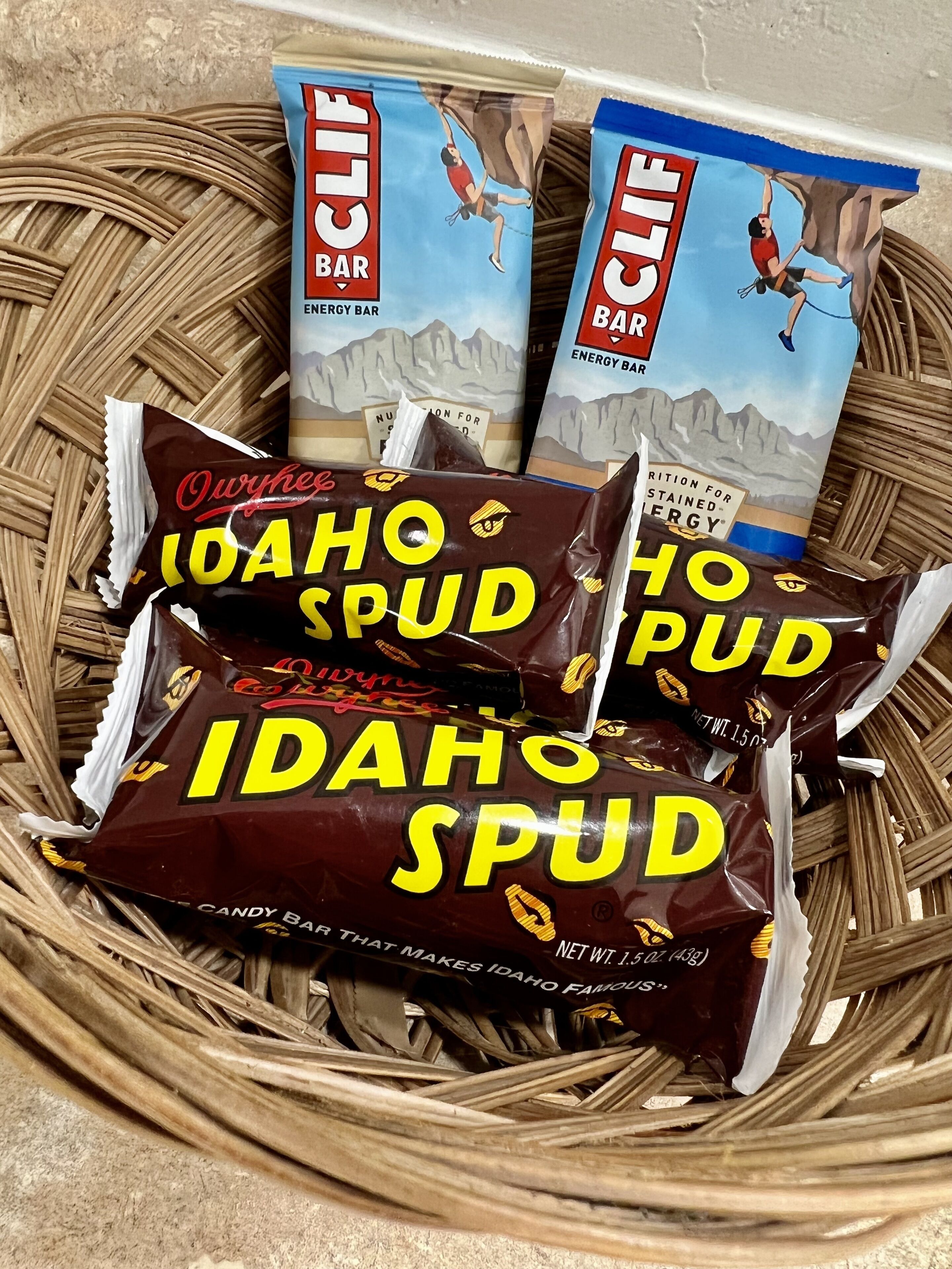 Three energy bars and two candy bars in a woven basket.