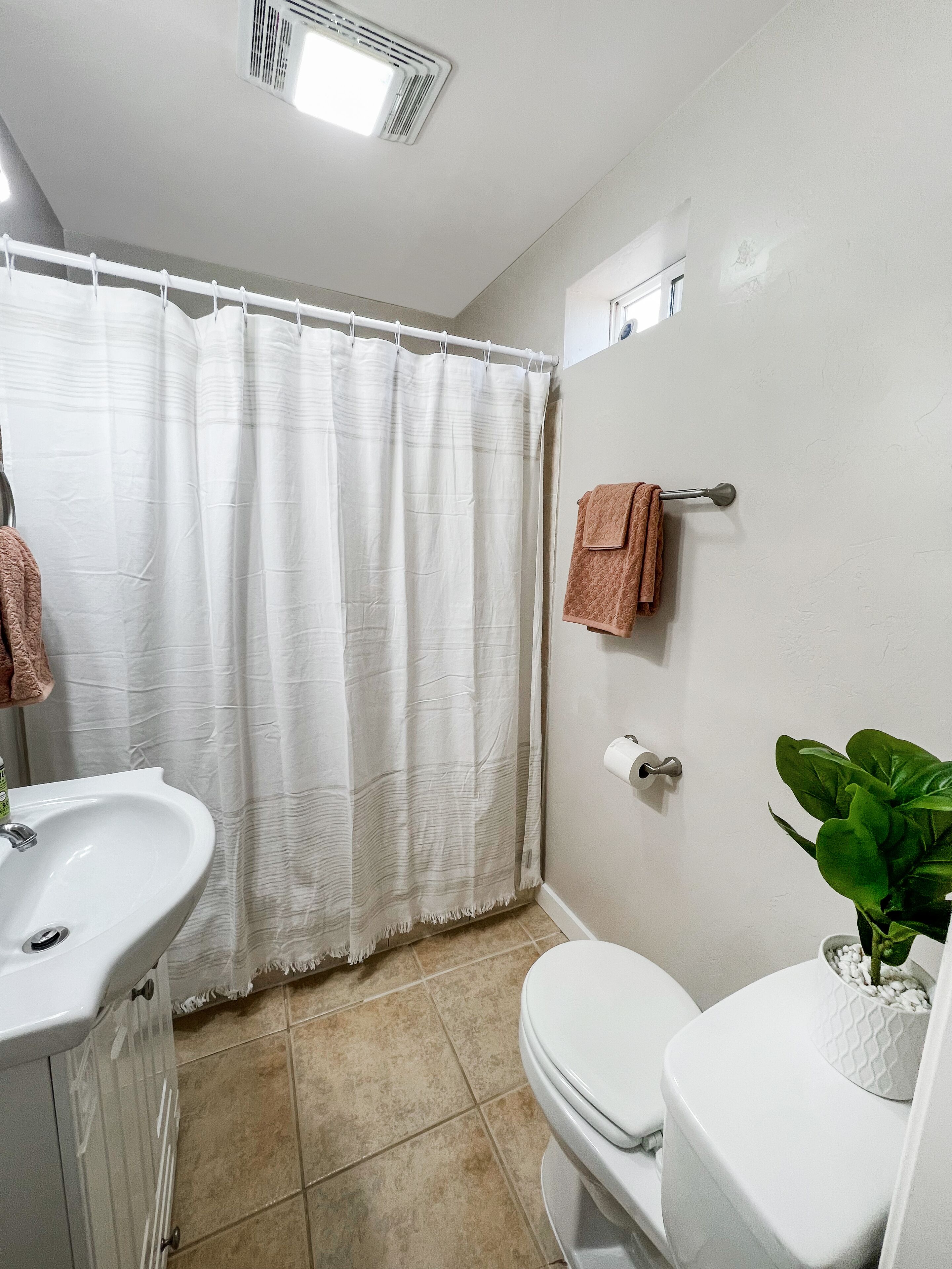 Une salle de bain avec un lavabo blanc, des toilettes et un rideau de douche.