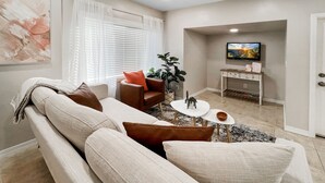 A living room with a sofa, armchairs, a coffee table, and a TV.