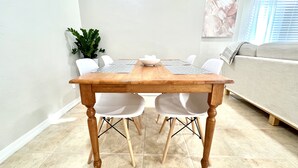 A dining table with a wooden top and four white chairs with black legs.
