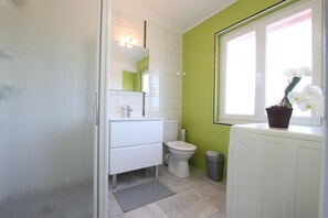 Bathroom features a white vanity, green accent wall, and a potted orchid.