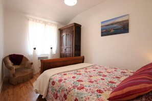 Cozy retreat with a comfortable bed, wooden wardrobe, and a chair for relaxation.