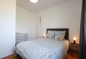 Cozy retreat with a neatly made bed, dresser, and bedside table.