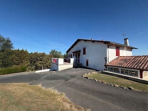 A two-story house with a red-tiled roof, a small attached garage, and a paved driveway.