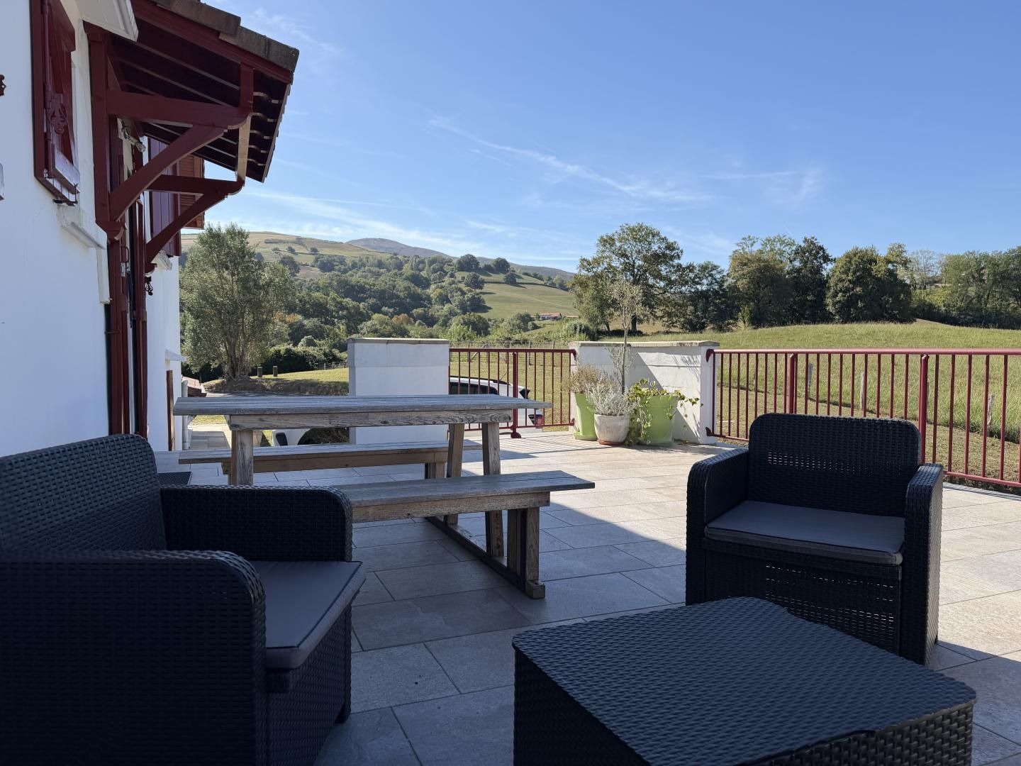 An outdoor patio with wicker furniture, a picnic table, and a view of the countryside.