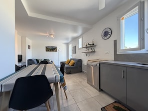 A modern living space with a dining area, kitchen, and a large window providing natural light.